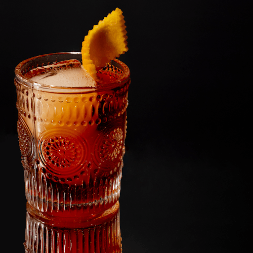 Amber cocktail in textured glass with orange peel garnish
